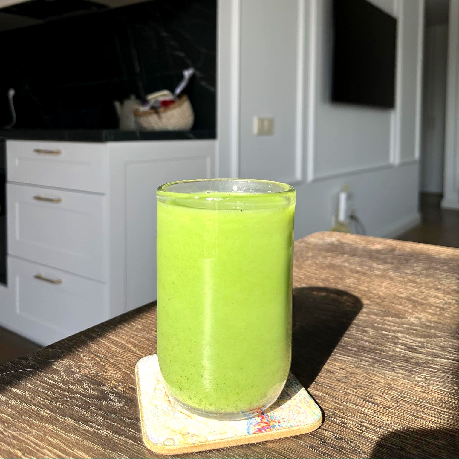Matcha latte stiklinėje, natūralioje šviesoje virtuvėje