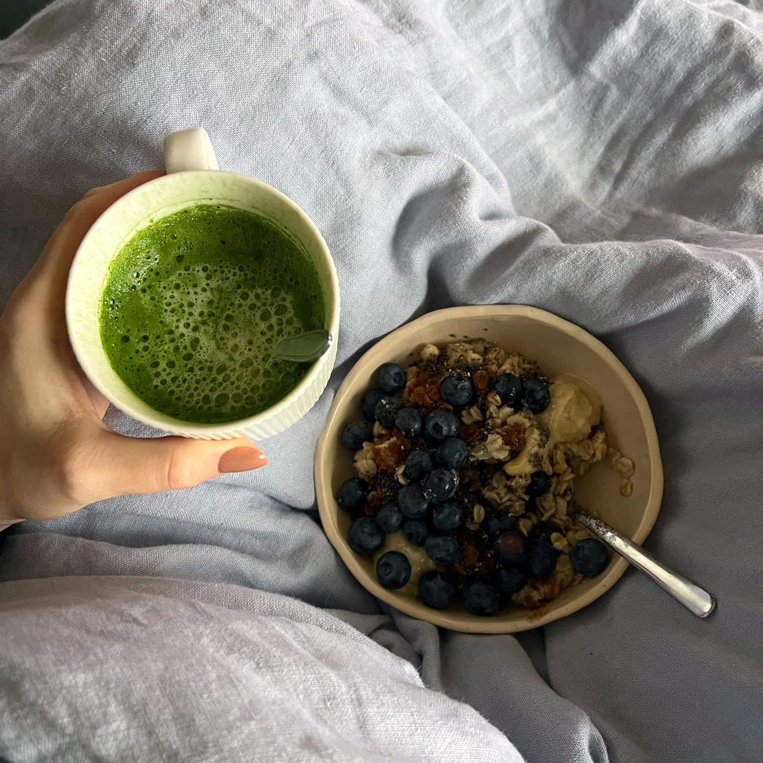 Puodelis matcha arbatos ir pusryčių dubenėlis su uogomis ir avižomis